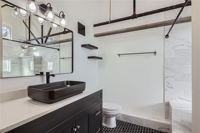 bathroom featuring vanity, tiled shower, and toilet