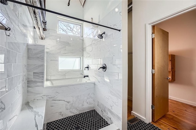 bathroom with wood-type flooring, plenty of natural light, and tiled shower