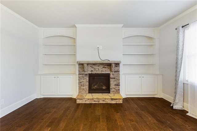 unfurnished living room featuring dark hardwood / wood-style floors, ornamental molding, a stone fireplace, and built in shelves