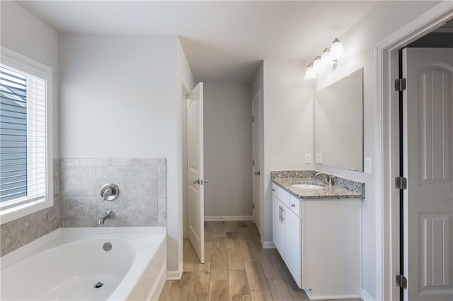 bathroom with vanity, hardwood / wood-style floors, a tub, and a healthy amount of sunlight