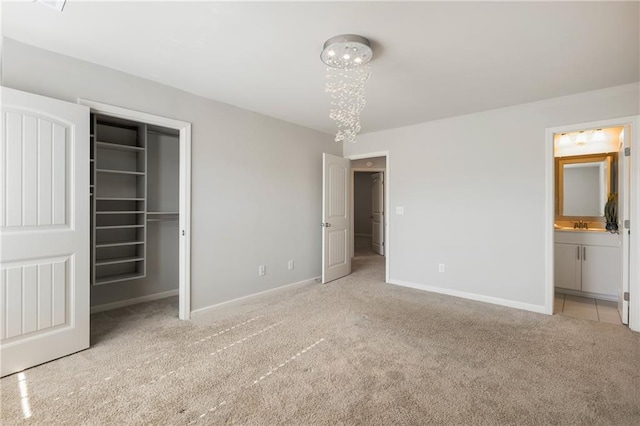 unfurnished bedroom with light colored carpet, connected bathroom, a closet, and a walk in closet