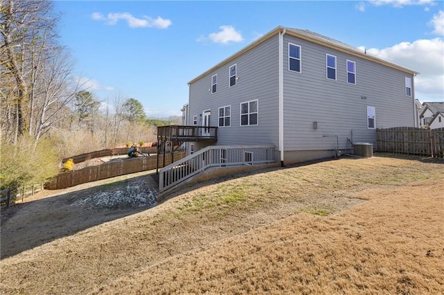 back of property with a wooden deck, central AC unit, and a lawn