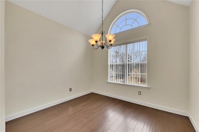 spare room with an inviting chandelier, dark hardwood / wood-style floors, and high vaulted ceiling