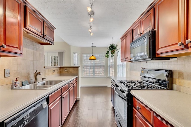 kitchen with pendant lighting, sink, backsplash, black appliances, and a textured ceiling