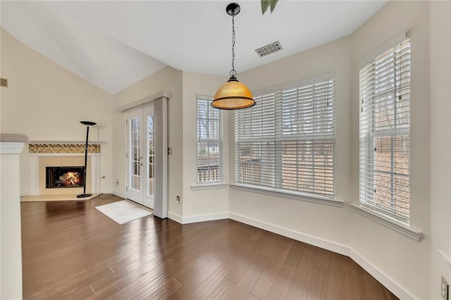 unfurnished dining area featuring lofted ceiling, hardwood / wood-style floors, and a healthy amount of sunlight