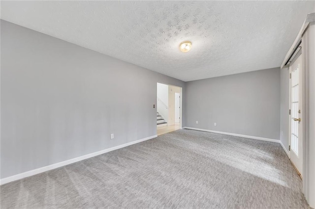 carpeted empty room featuring a textured ceiling