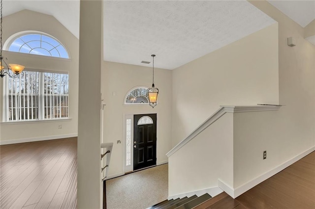 entryway with vaulted ceiling, dark hardwood / wood-style floors, a textured ceiling, and a chandelier