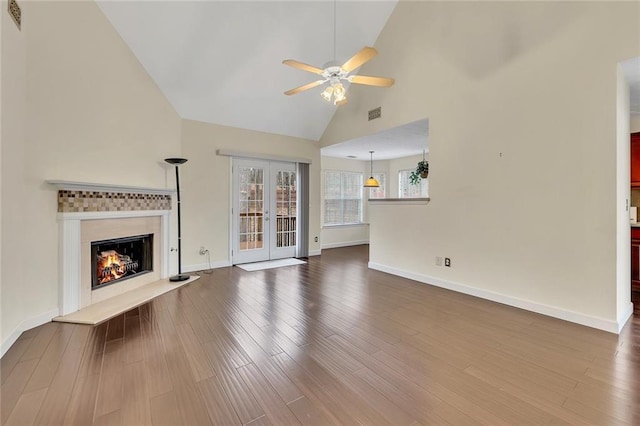 unfurnished living room featuring hardwood / wood-style flooring, high vaulted ceiling, ceiling fan, and french doors