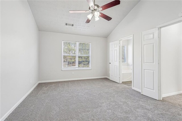 unfurnished bedroom with vaulted ceiling, light colored carpet, ensuite bath, and ceiling fan