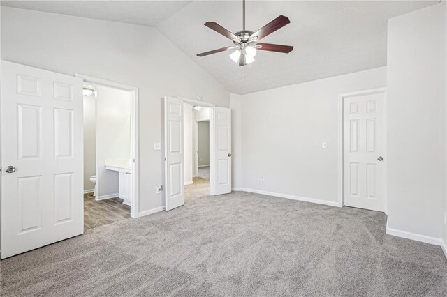 unfurnished bedroom with high vaulted ceiling, ceiling fan, ensuite bathroom, and light carpet