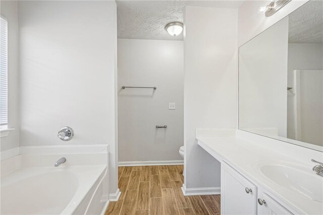 bathroom with a bathing tub, hardwood / wood-style floors, a textured ceiling, and toilet