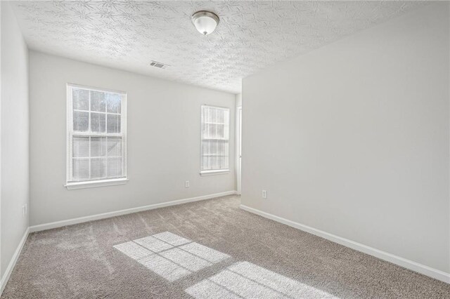 empty room with carpet floors and a textured ceiling