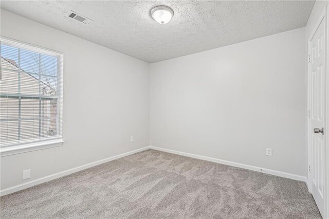 carpeted empty room with a textured ceiling