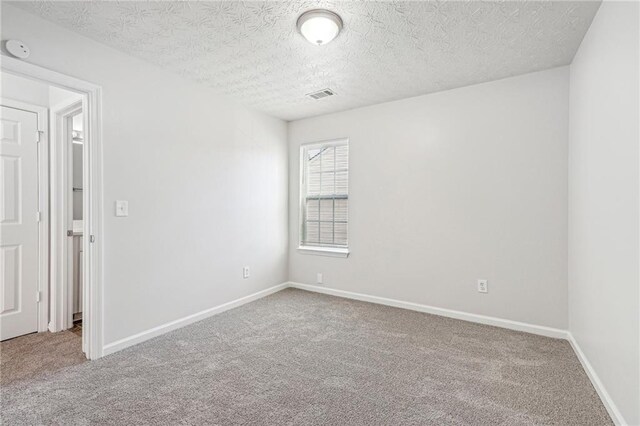 carpeted spare room with a textured ceiling