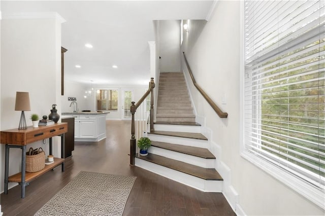 stairway with hardwood / wood-style floors, ornamental molding, and sink