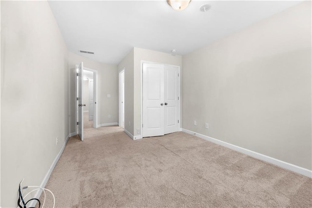 unfurnished bedroom with light carpet and a closet