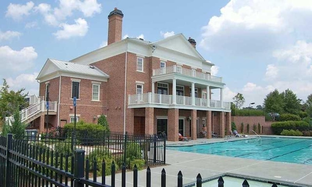 back of house with a community pool, a patio area, and a balcony