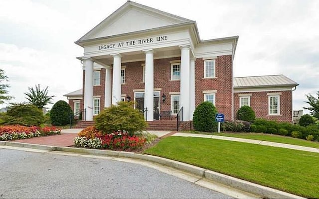 neoclassical home featuring a front lawn