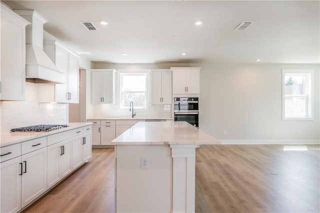 4202 Adler Cir, Buford, GA 30519 - kitchen with decorative backsplash, a healthy amount of sunlight, custom range hood, and gas cooktop