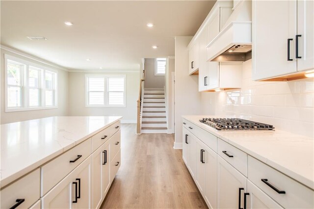 4202 Adler Cir, Buford, GA 30519 - kitchen featuring appliances with stainless steel finishes, premium range hood, white cabinetry, light wood-style flooring, and light stone counters