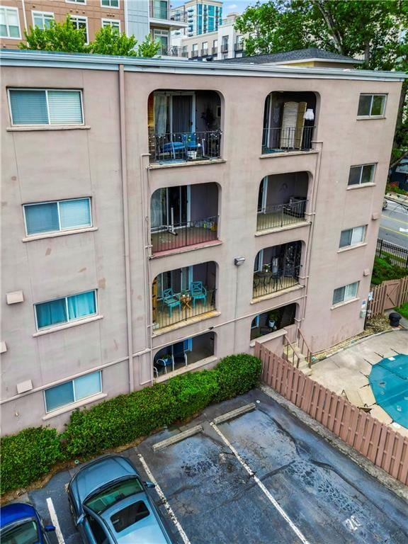 view of apartment building / complex featuring uncovered parking and fence