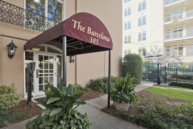 entrance to property featuring stucco siding and fence