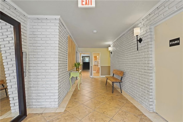hall with brick wall, light tile patterned flooring, and ornamental molding