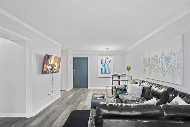 living area with wood finished floors, a chandelier, crown molding, and baseboards