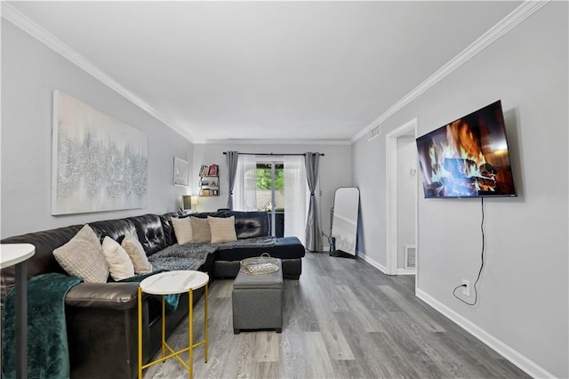 living room featuring wood finished floors, ornamental molding, and baseboards