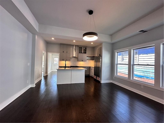 kitchen with hanging light fixtures, wall chimney exhaust hood, visible vents, and dark wood-style flooring