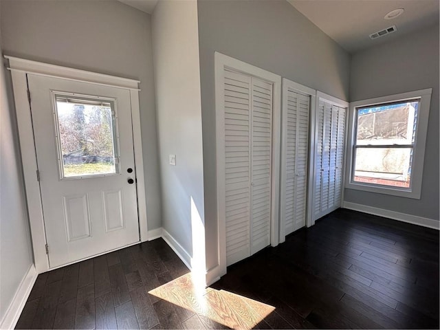 foyer entrance with dark wood-style floors, plenty of natural light, visible vents, and baseboards