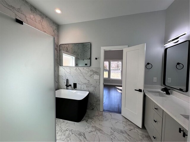 bathroom with marble finish floor, recessed lighting, vanity, and tile walls