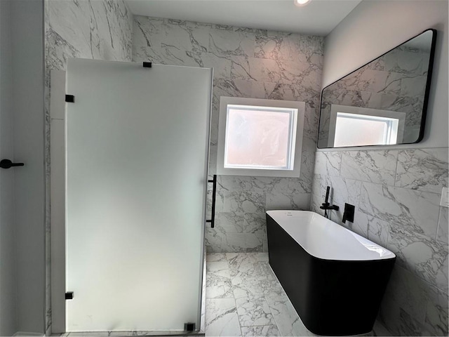 full bathroom with marble finish floor and a freestanding bath