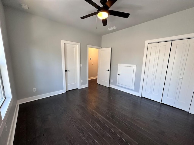 unfurnished bedroom featuring dark wood-type flooring, a ceiling fan, visible vents, baseboards, and a closet