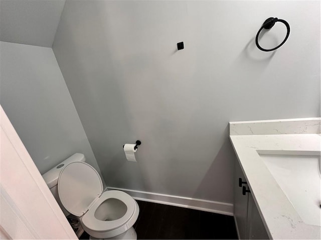 bathroom featuring toilet, a sink, baseboards, and wood finished floors