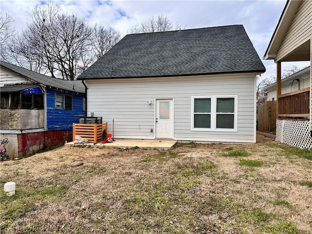 back of property with roof with shingles, a lawn, a patio, and fence