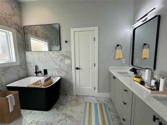 full bath featuring double vanity, a soaking tub, a sink, marble finish floor, and tile walls