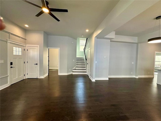 interior space featuring dark wood-type flooring, ceiling fan, baseboards, and stairs