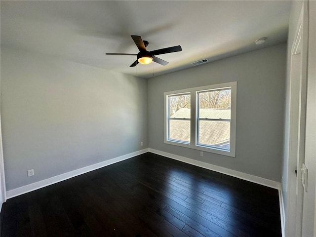 spare room with dark wood-style floors, visible vents, baseboards, and a ceiling fan