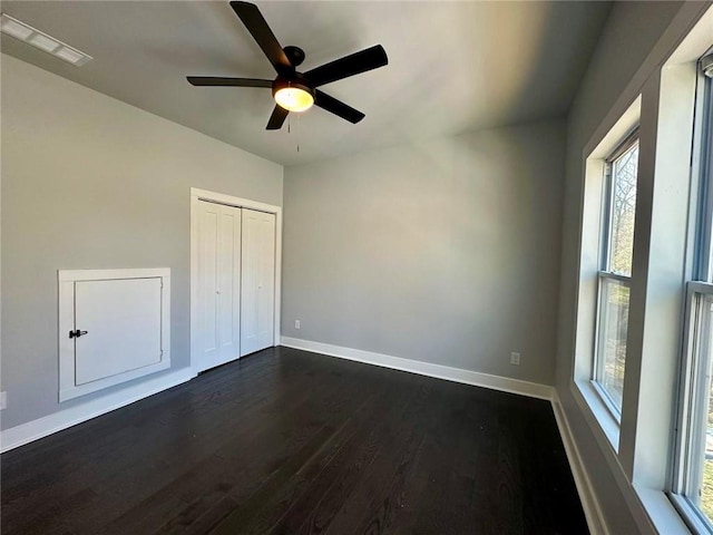 unfurnished bedroom featuring baseboards, visible vents, a ceiling fan, dark wood-style floors, and a closet