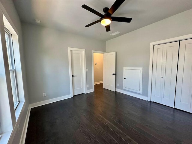 unfurnished bedroom featuring a ceiling fan, visible vents, baseboards, a closet, and dark wood-style floors