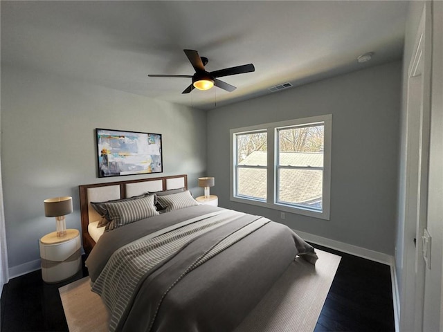 bedroom featuring a ceiling fan, visible vents, baseboards, and wood finished floors