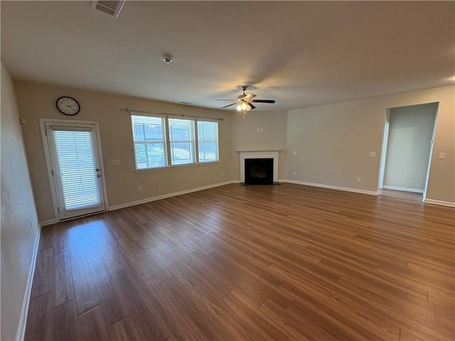 unfurnished living room featuring visible vents, ceiling fan, baseboards, a fireplace with flush hearth, and wood finished floors