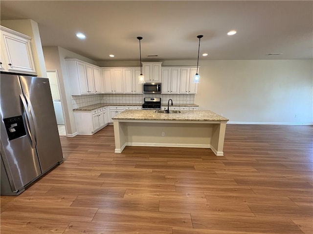 kitchen featuring decorative backsplash, stainless steel appliances, wood finished floors, and a sink