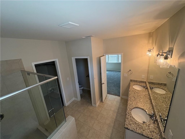 full bath featuring a shower stall, toilet, double vanity, and a sink