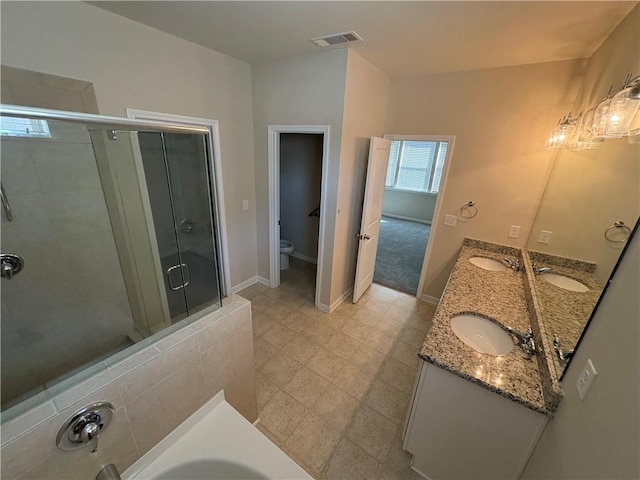 full bath featuring toilet, a stall shower, a sink, double vanity, and baseboards