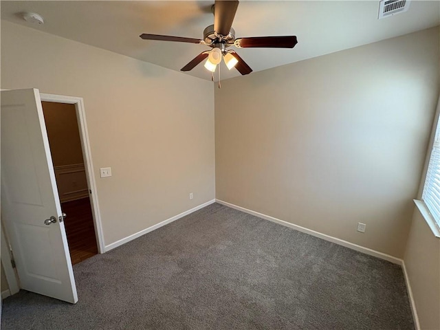 empty room featuring baseboards, visible vents, and dark carpet