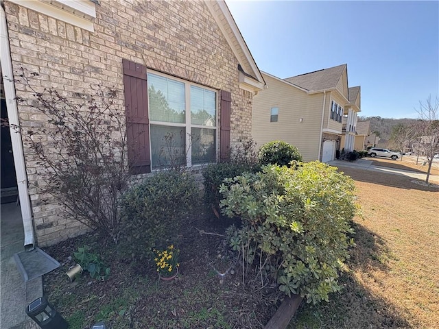 view of side of home with brick siding, concrete driveway, and an attached garage