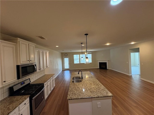 kitchen with visible vents, a sink, tasteful backsplash, open floor plan, and stainless steel appliances