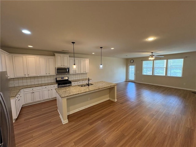 kitchen featuring decorative backsplash, dark wood-type flooring, appliances with stainless steel finishes, and a sink